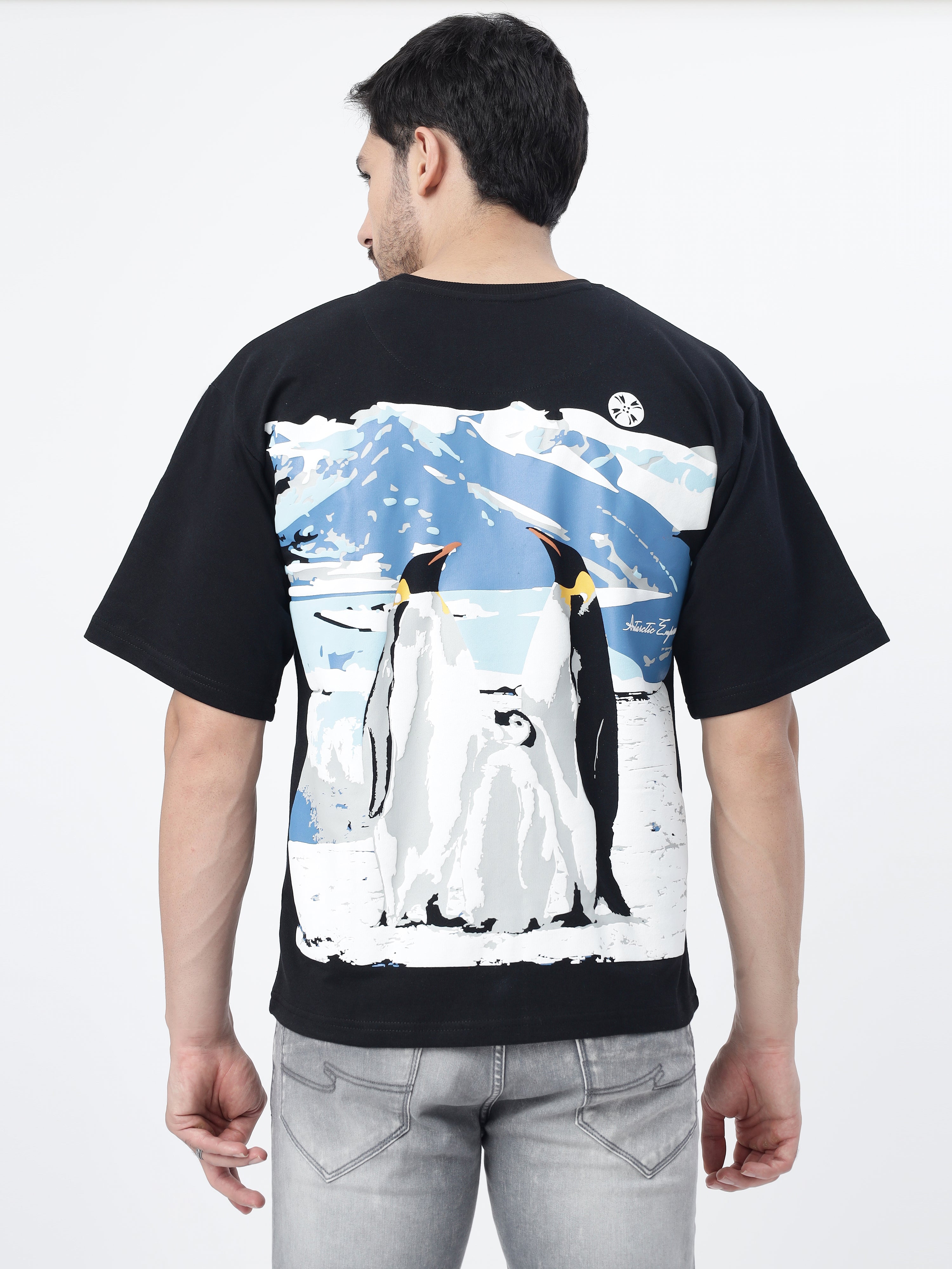 Model showcasing the back print of Black antarctic emperor oversized t-shirt, on a white background.