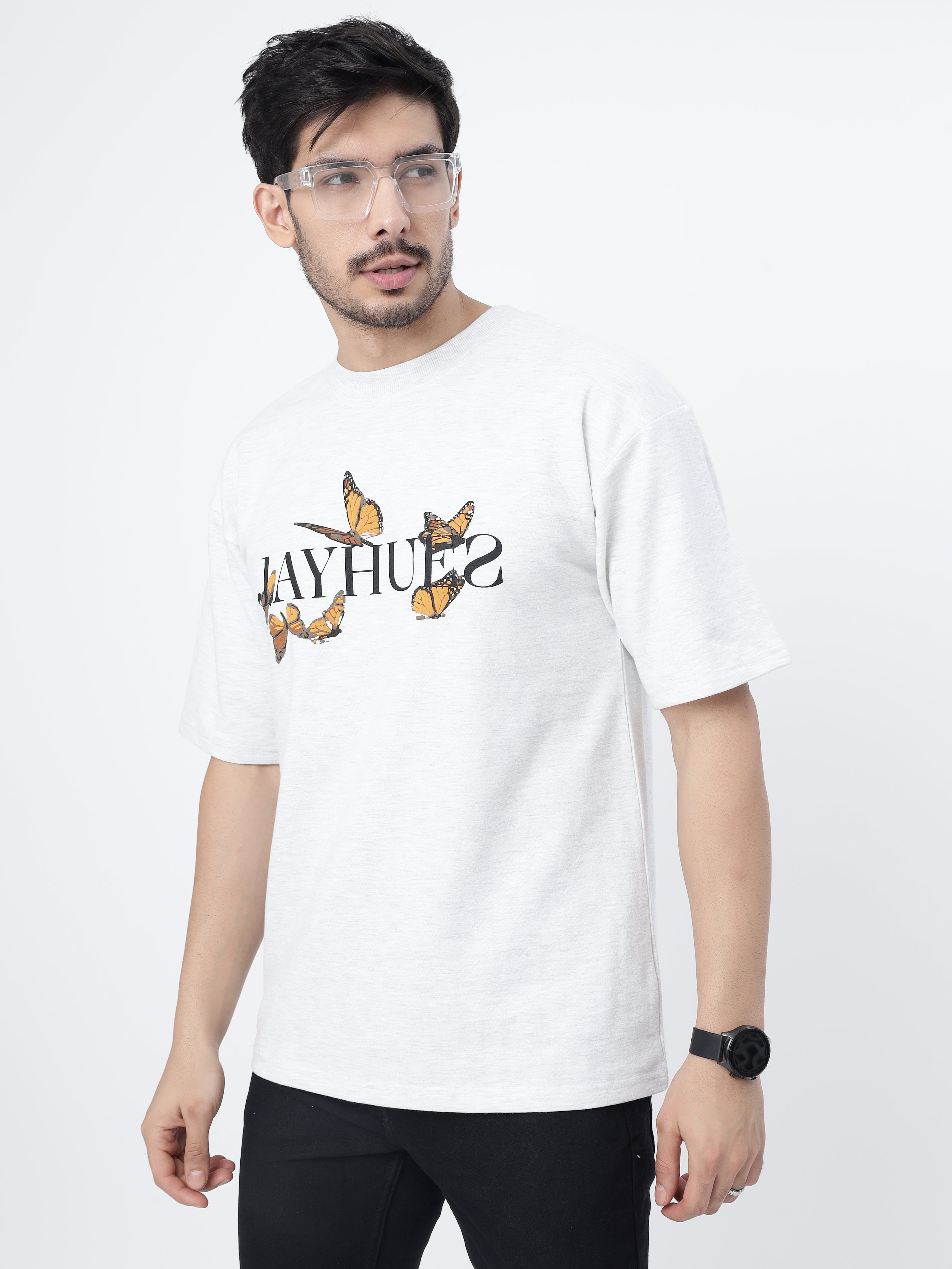 Model showcasing the front print of White orange butterflies oversized t-shirt on a grey background.