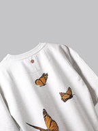 Back side of White orange butterflies oversized t-shirt on a grey background.