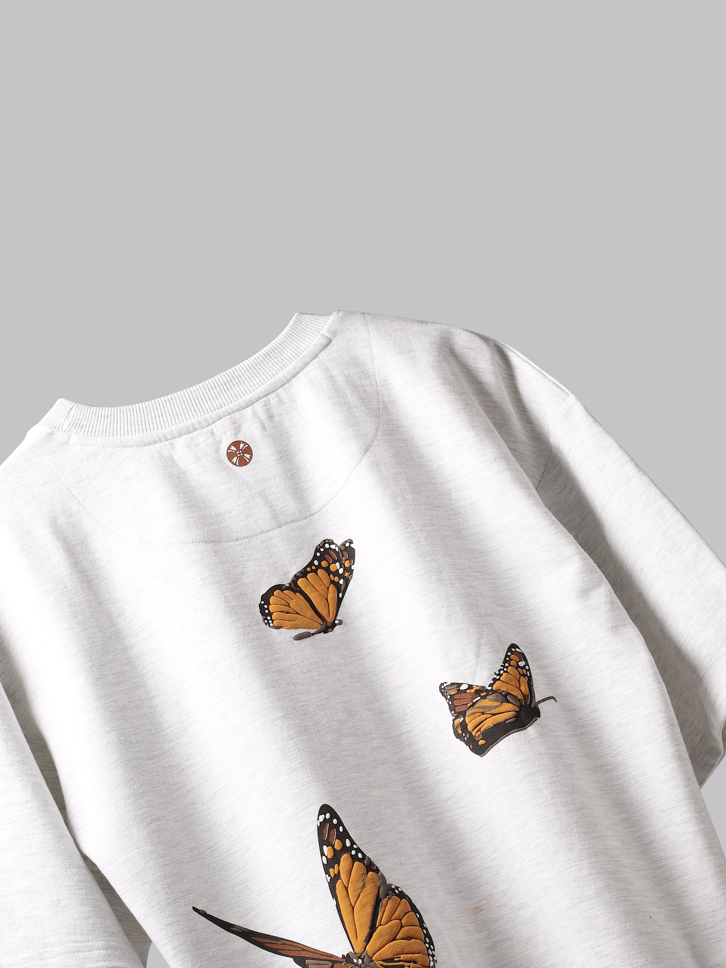 Back side of White orange butterflies oversized t-shirt on a grey background.