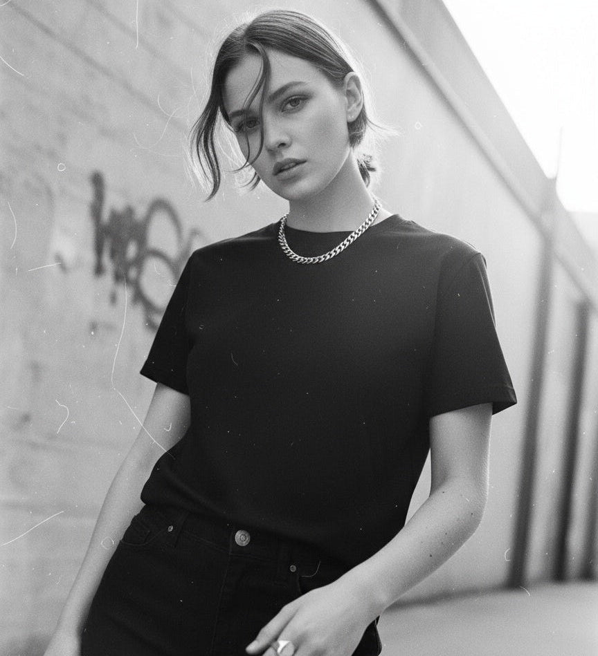 Person wearing a jayhues basic black t-shirt  against a graffiti-covered wall.