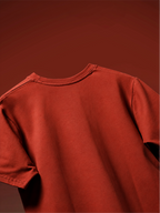 A close-up of the rust basic t-shirt from the back showing the back neckline and shoulder seams, set against a matching solid rust-red background.