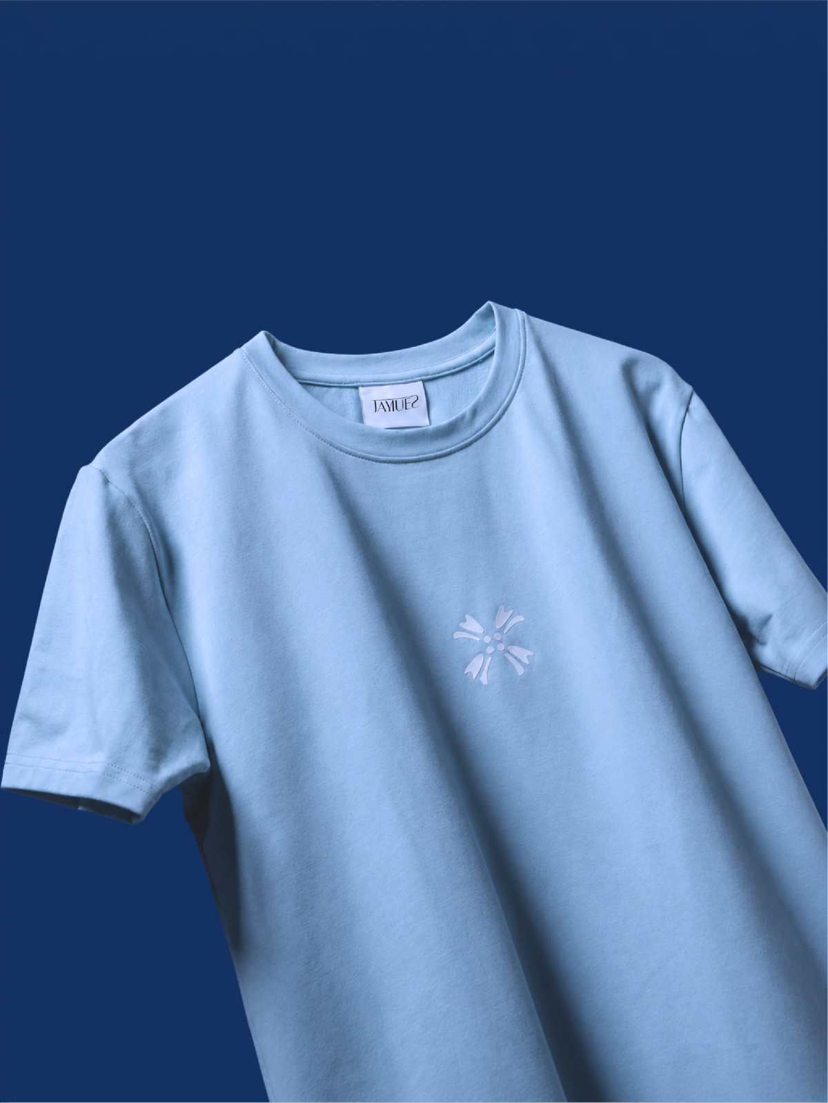 A light blue basic mark t-shirt with a small white hd printed logo on the chest, displayed against a solid dark blue background.
