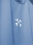 A close-up of the light blue basic mark t-shirt featuring the white HD printed logo on the chest.