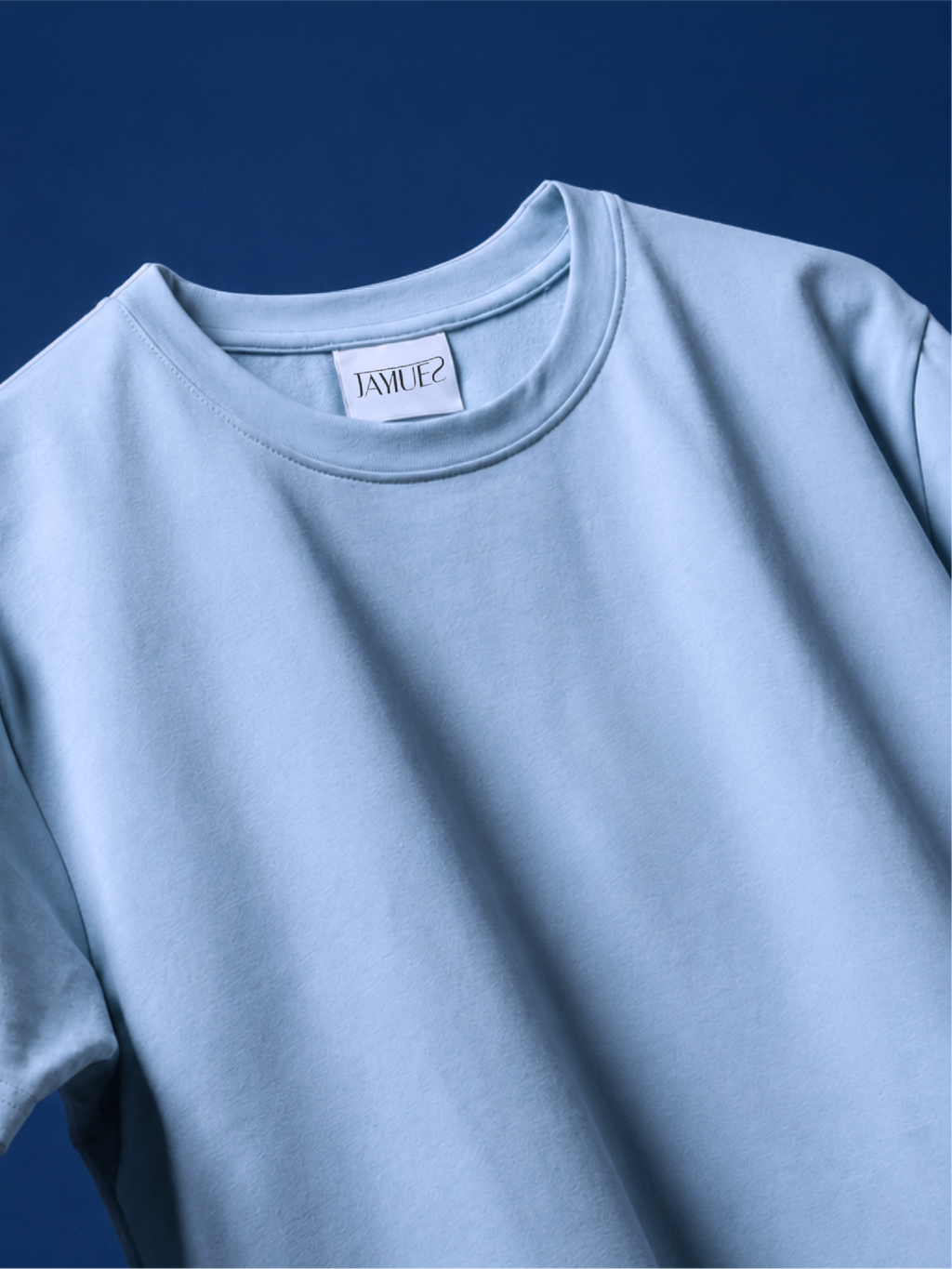 A close-up of a light blue basic t-shirt against a dark blue background.