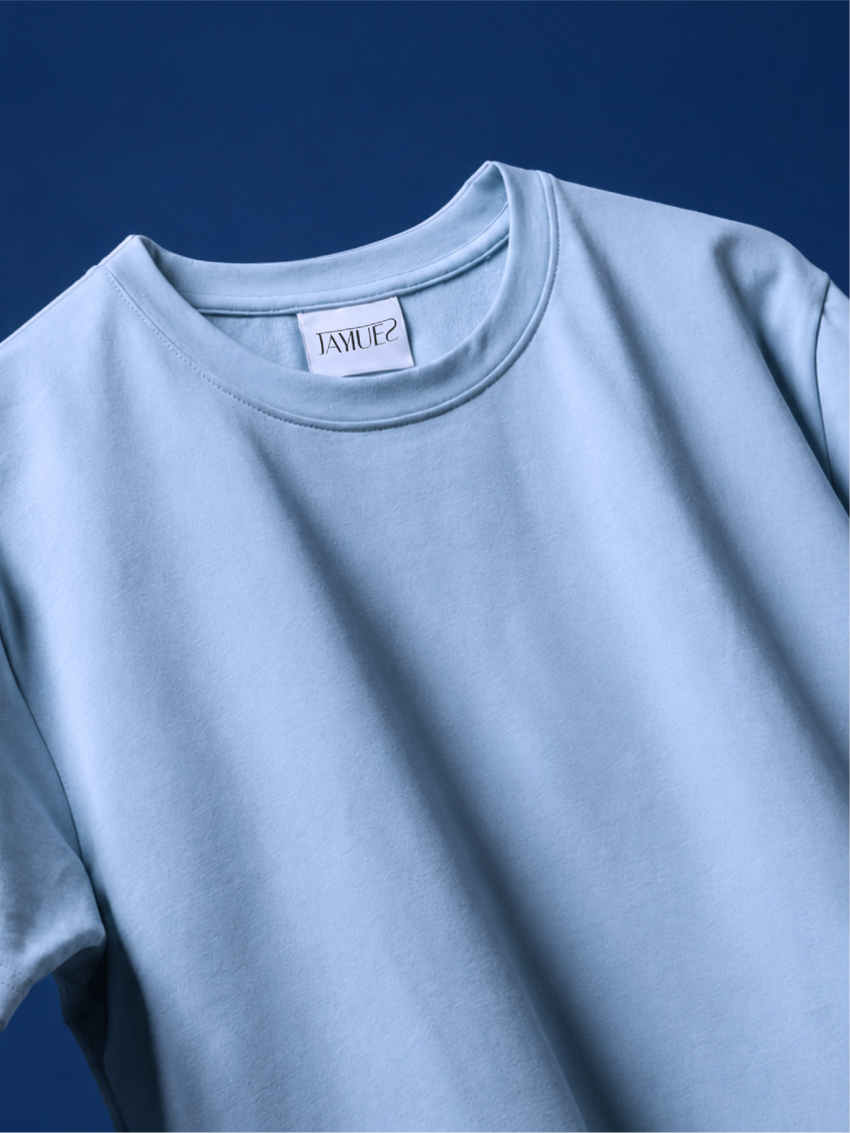 A close-up of a light blue basic t-shirt against a dark blue background.