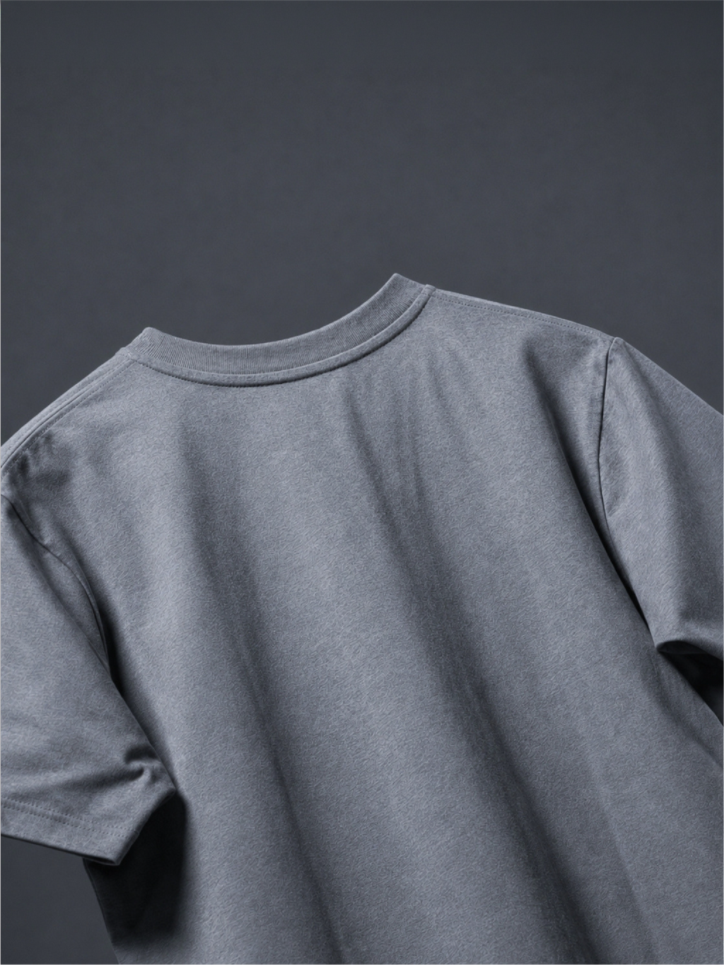 Close-up of the back of the grey basic t-shirt against a dark gray background.