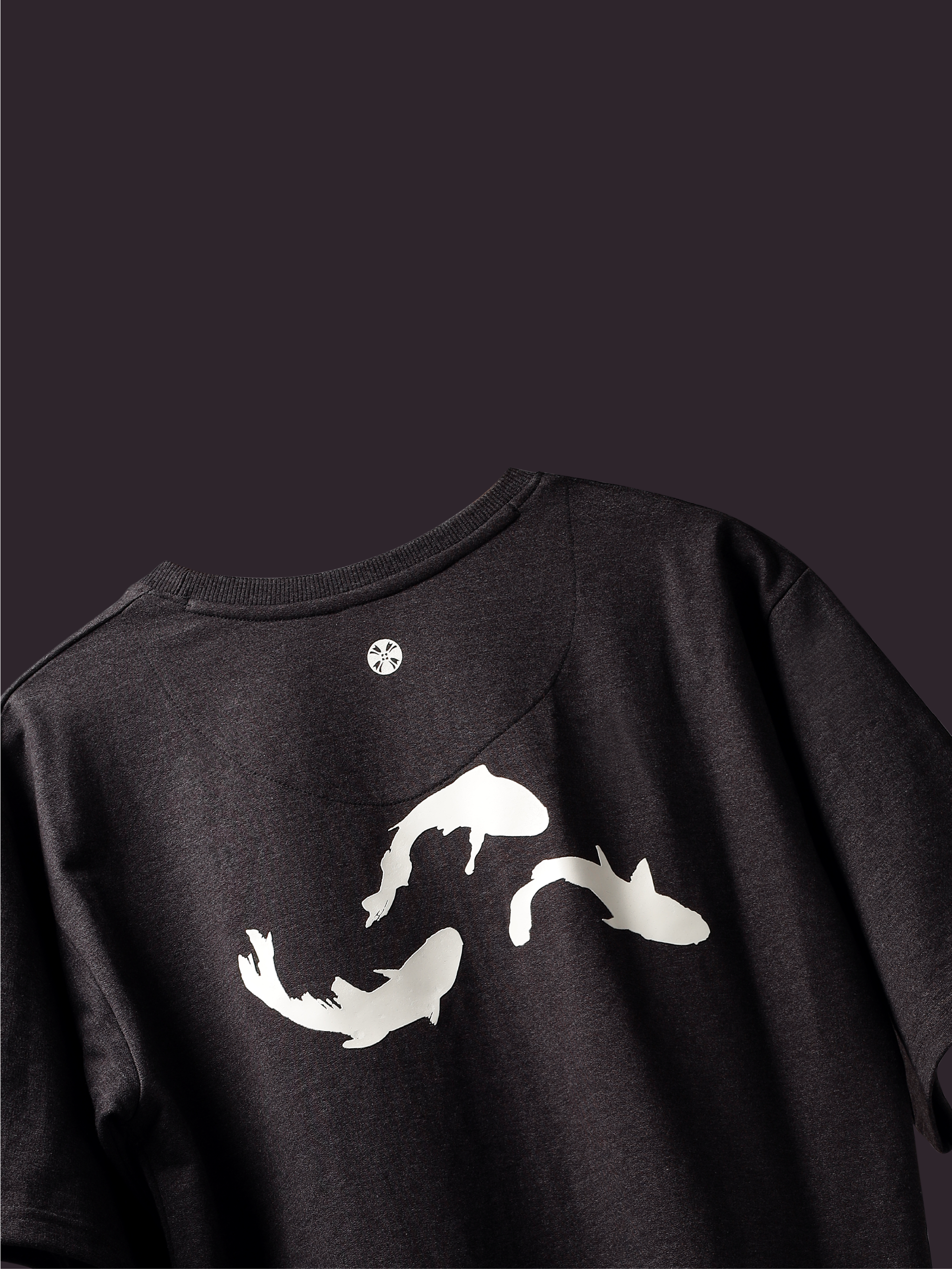 Back side of Charcoal Pisces Koi oversized t-shirt on a dark background.