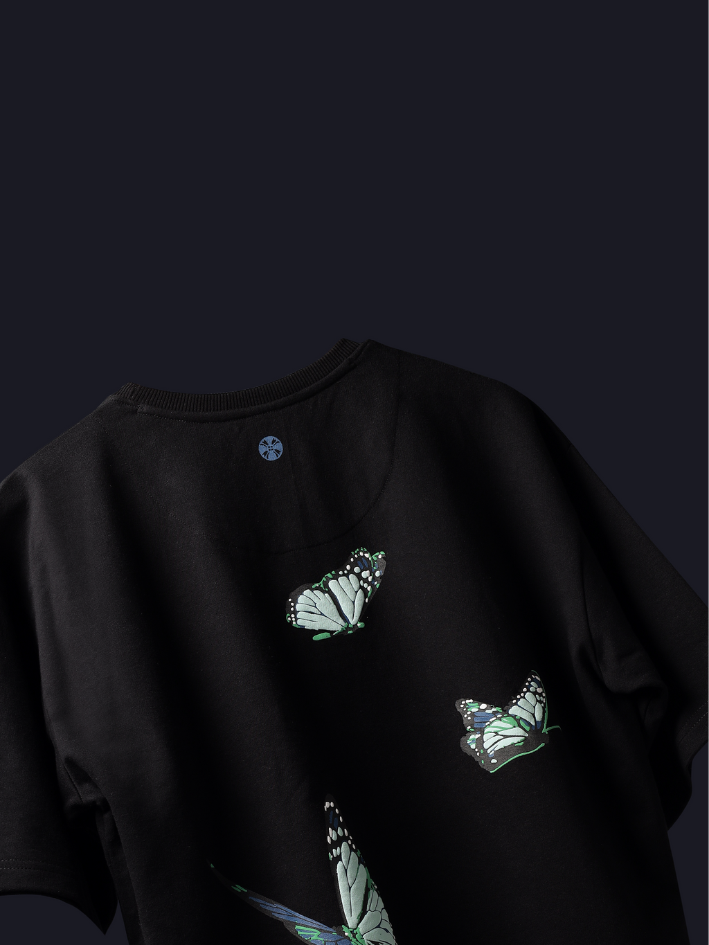 Back side of Black blue butterflies oversized t-shirt on dark background.