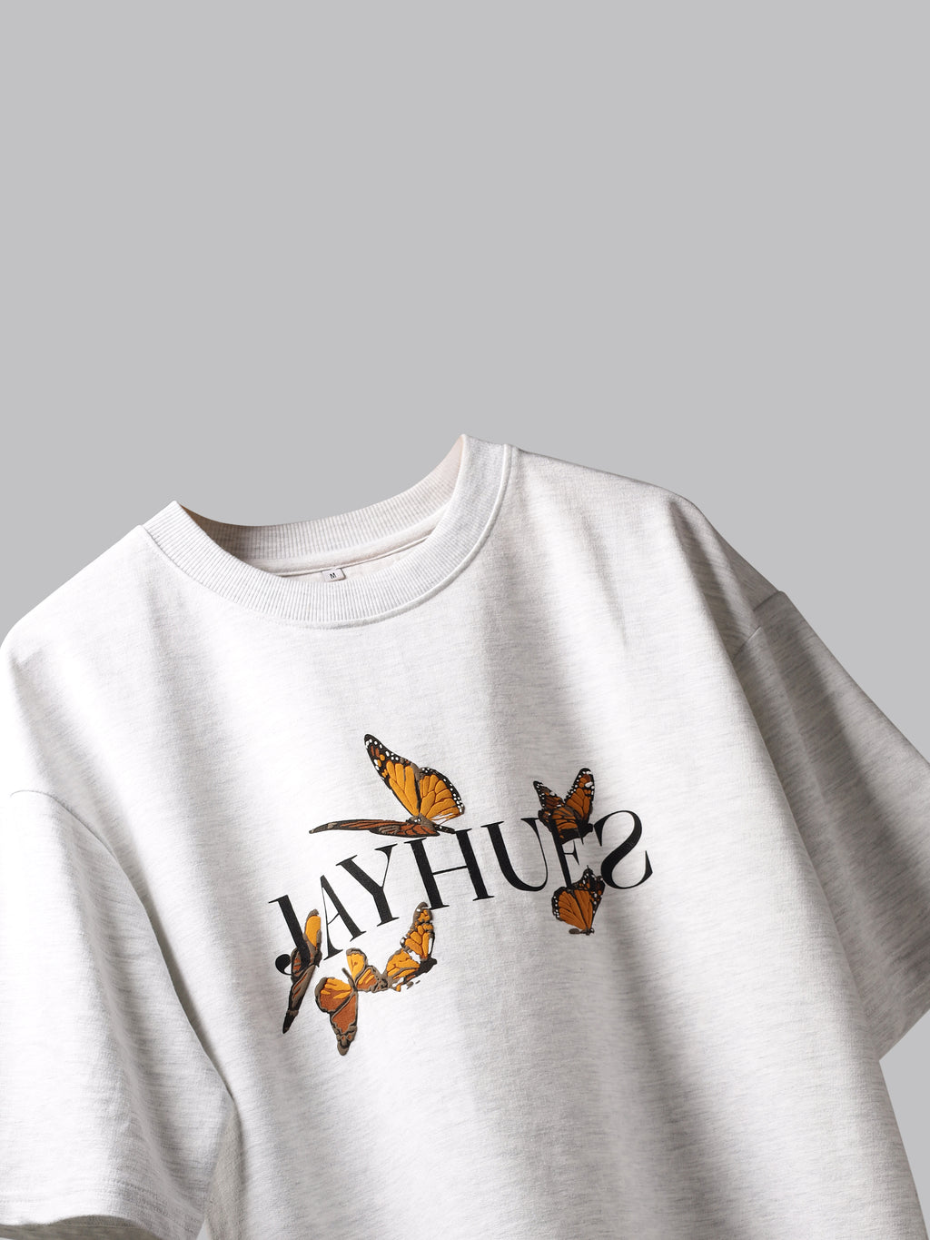 White orange butterflies oversized t-shirt on a grey background.