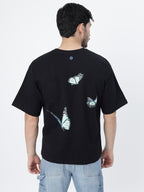 Model showcasing the back side of Black blue butterflies oversized t-shirt on a white background.